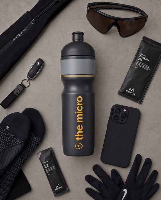 The Micro race bottle in a race day flat lay with gels, sunglasses and phone