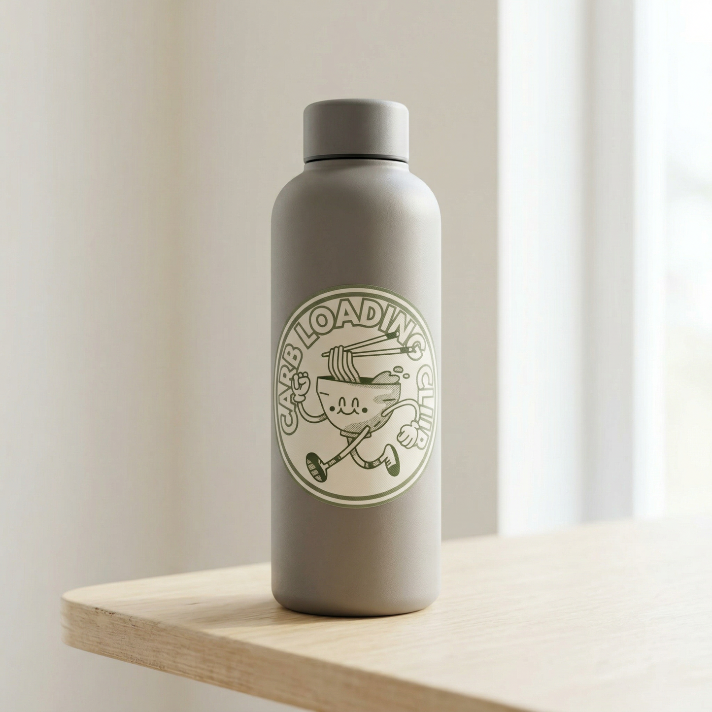Gray water bottle with a Carb Loading Club sticker on a wooden surface