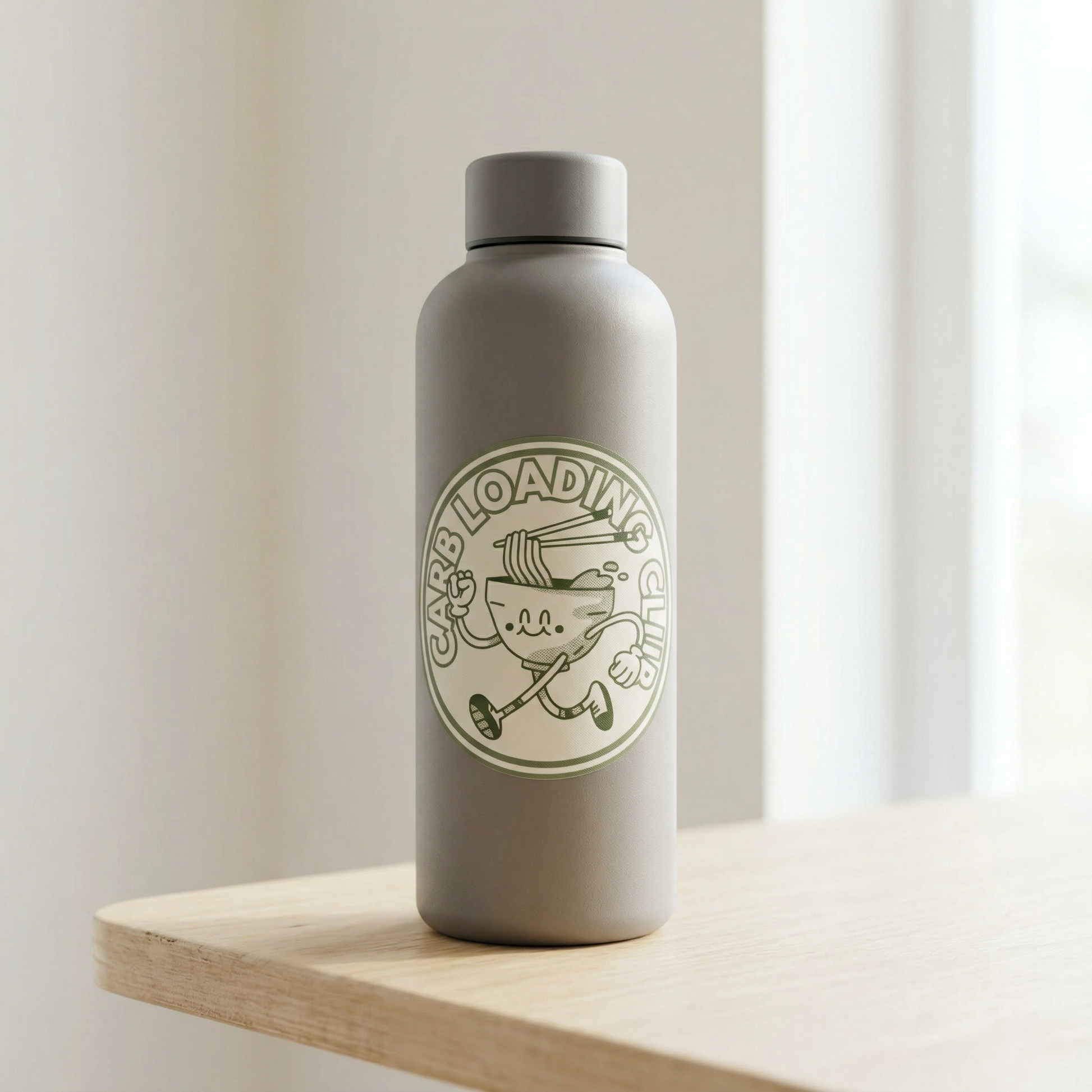 Gray water bottle with a Carb Loading Club sticker on a wooden surface