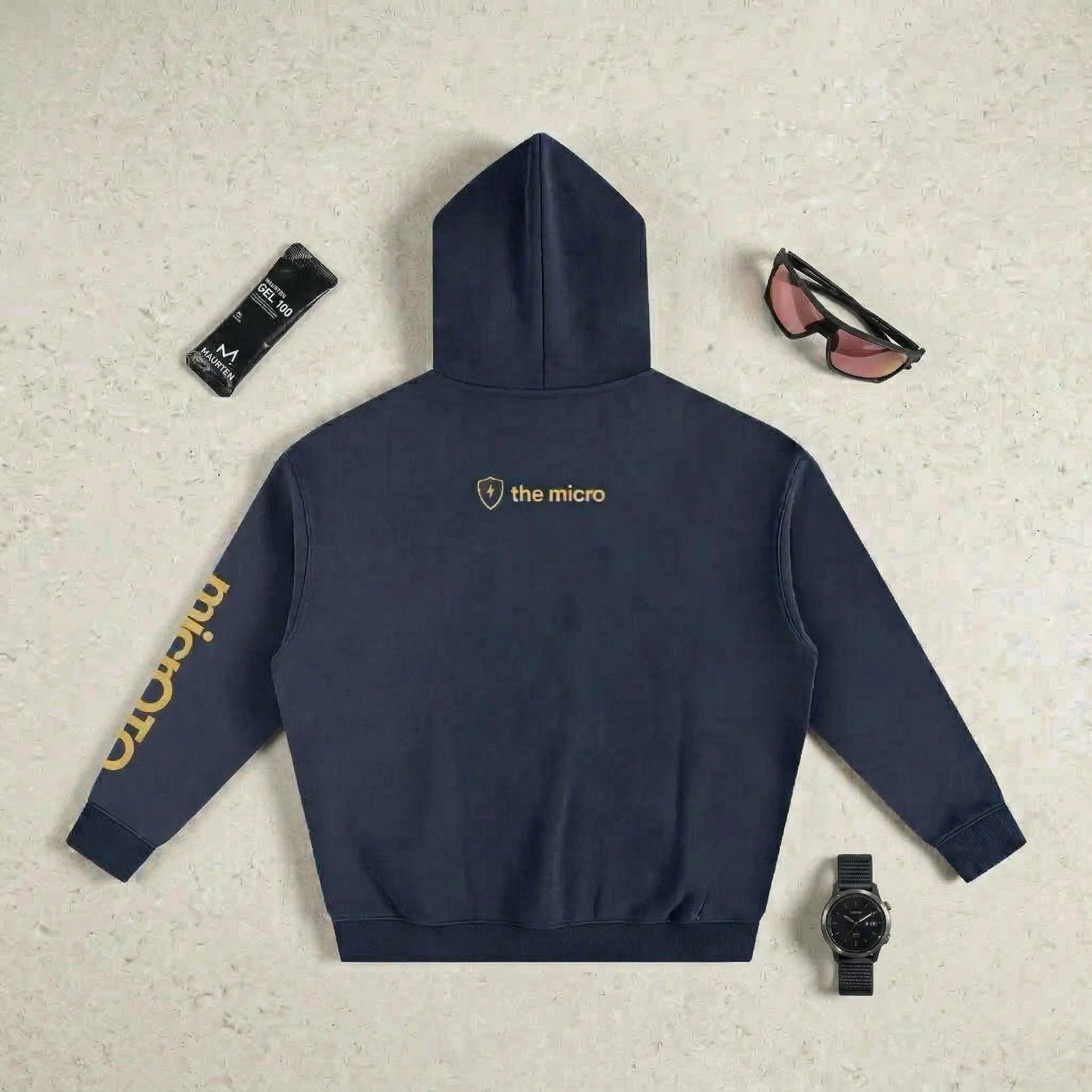 Navy micrOTQ hoodie with 'the micro' logo on a textured surface with accessories.
