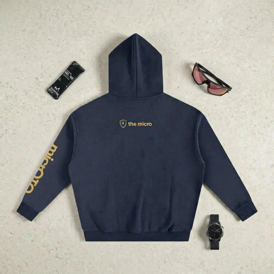 Navy micrOTQ hoodie with 'the micro' logo on a textured surface with accessories.
