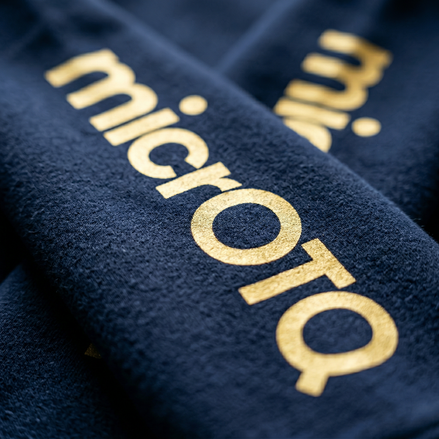 Close-up of a textured surface with 'microTQ' printed in gold.