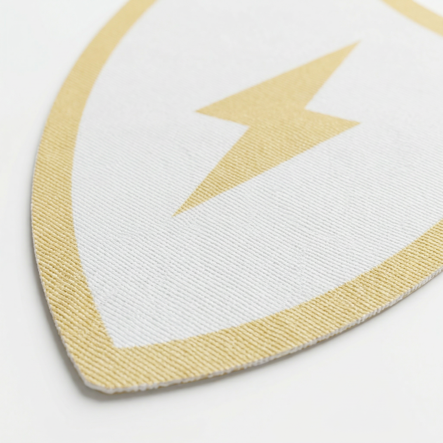 Close-up of a white and gold shield-shaped object on a light gray background